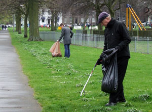 Malcolm in cap, jacket and gloves with a litter picker on Leith Links