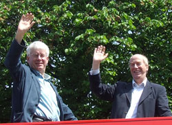 Malcolm in an open neck shirt waving from the open top bus with Mark Lazarowicz, Westminster MP for Edinburgh North & Leith